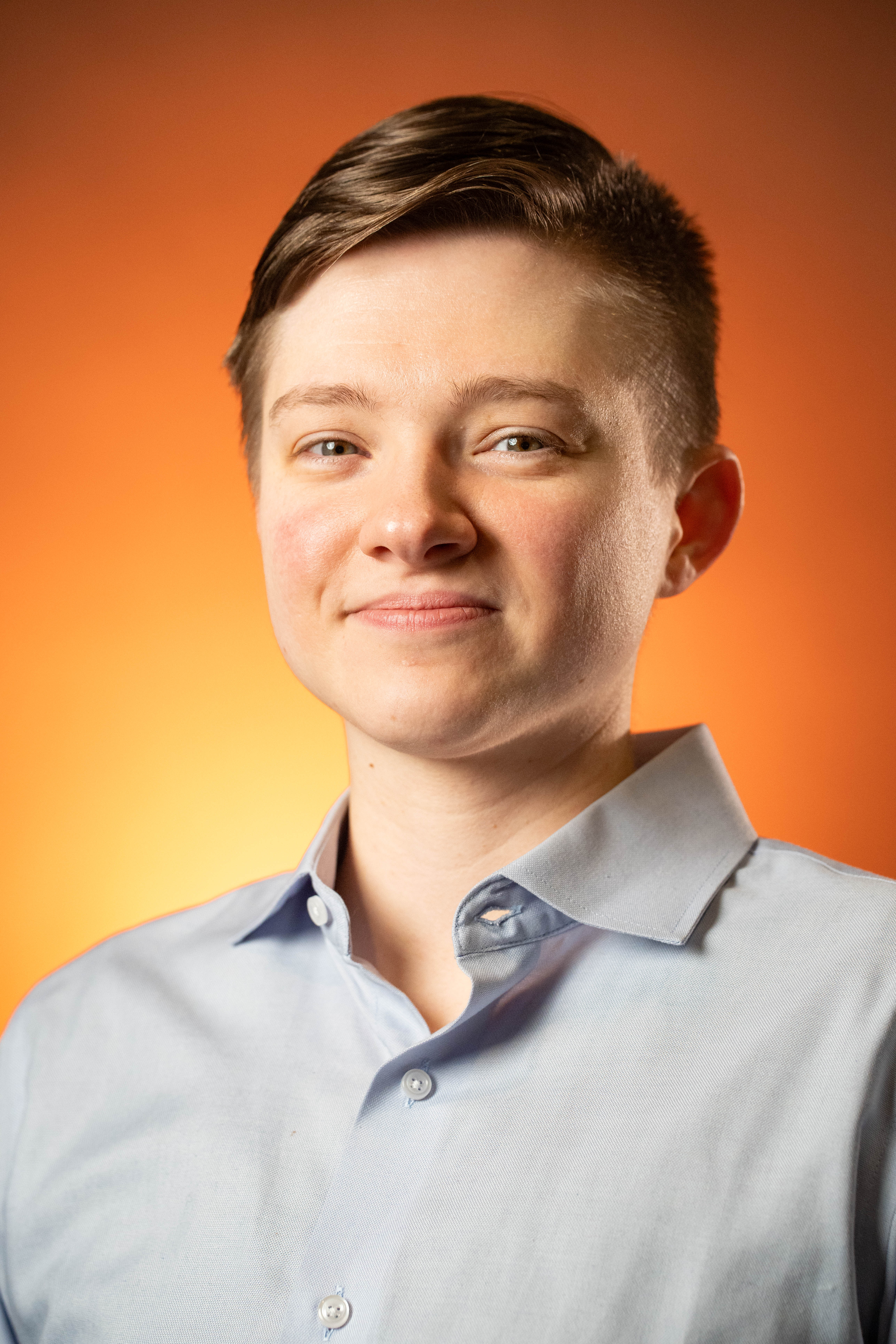 Professional headshot — orange background, blue button-down